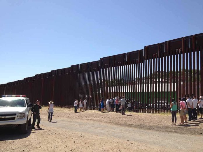 Border fence with group of people and a patrol vehicle