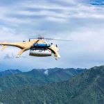 Cargo drone helicopter flying over green mountain range