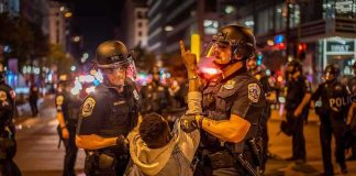 Police officers detain a protester at night on a city street