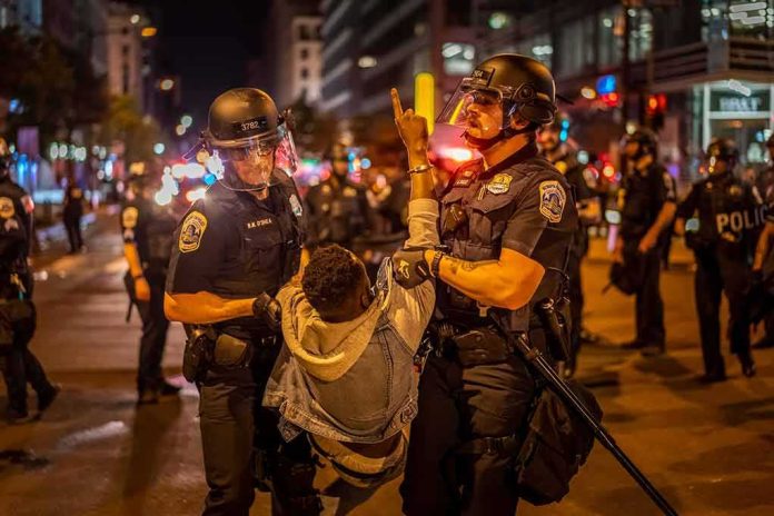 Police officers detain a protester at night on a city street