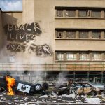 Burning overturned police car in front of a damaged building
