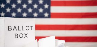 DOJ Freezes Alaska Count Over Twin Names Ballot box with papers in front of an American flag