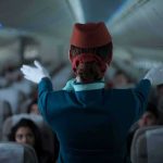 Flight attendant giving safety demonstration in airplane aisle
