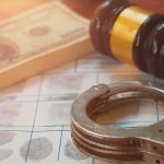 Handcuffs on fingerprint form with gavel and cash